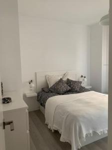 a white bedroom with a bed and a white wall at Apto residencial piscina centro-Parking in Jaén