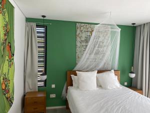 Schlafzimmer mit grünen Wänden und einem Bett mit weißer Bettwäsche in der Unterkunft Pomelo 3 in Ruisseau Créole
