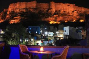 a table and chairs with a view of a city at night at Karma Heritage Guest House in Jodhpur