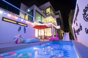 uma casa com uma piscina com um guarda-sol em Pupae Pool Villa Pattaya em South Pattaya