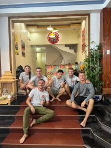 um grupo de homens sentados nos degraus de uma casa em Ha Giang Donkey hostel em Ha Giang