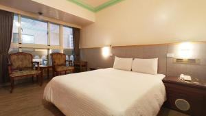 a hotel room with a bed and a table and chairs at Longchi Hot-Spring Hotel in Jiaoxi
