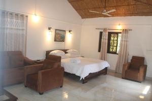 a bedroom with a bed and two chairs at RED HOUSE - AGONDA BEACH in Agonda
