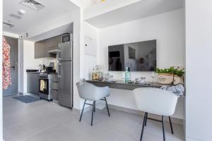 a kitchen with a counter and two white chairs at Frank Porter - Bella Rose in Dubai