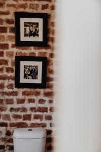 a brick wall with two pictures above a toilet at Eclectic Heritage Paradise Simon's Town in Simonʼs Town +70 photos