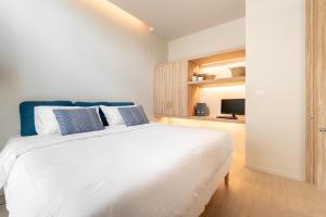 a bedroom with a large white bed with blue pillows at Silom Nara in Bangkok