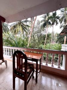a wooden table and chair on a balcony with palm trees at RED HOUSE - AGONDA BEACH in Agonda