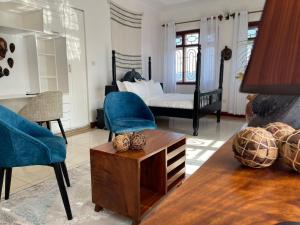 ein Wohnzimmer mit einem Bett, einem Tisch und Stühlen in der Unterkunft The Jewel and the Lake in Jinja