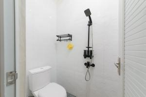 ein weißes Bad mit einem WC und einem Mikrofon in der Unterkunft Urbanview Hotel Binwa Syariah Bandar Lampung in Hajimana