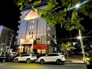 zwei weiße Autos, die vor einem Gebäude geparkt sind in der Unterkunft Aristocrat Residence & Hotel in Sihanoukville
