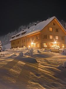 a large building in the snow at night at Gähwindehof Mountain Ranch Resort in Oberstaufen