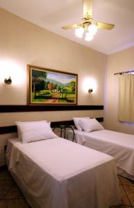 two beds in a room with a painting on the wall at Hotel Santa Rita in Indaiatuba