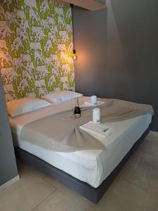 Barocco Island Studios في سكالا بوتامياس: سرير مع طاولة مع زجاجة من النبيذ عليه