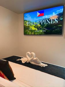 a tv hanging on a wall above a bed at CLOCKWORKORANGE Luxury Suites 4-Minutes Away To Airport in Mactan