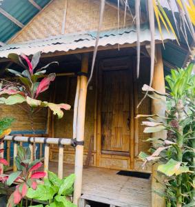 een klein huis met een houten deur en een aantal planten bij Farmer homestay in Tetebatu