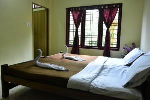 sypialnia z łóżkiem z dwoma pomnikami zwierząt w obiekcie Eshwari Cottage w mieście Madikeri