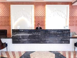 a man standing behind a counter in a lobby at SWARN INN AND SUITES in Muzaffarnagar