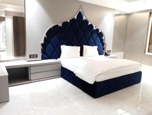 een groot bed met een blauw hoofdeinde in een kamer bij SWARN INN AND SUITES in Muzaffarnagar