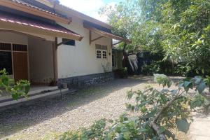 a white house with a porch and a yard at OYO 93435 Yuda Family Homestay in Lembuak