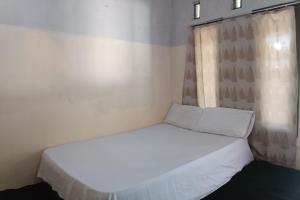 a white bed in a room with a window at OYO 93435 Yuda Family Homestay in Lembuak