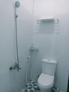 a white bathroom with a toilet and a shower at Quanza Hotel in Banda Aceh