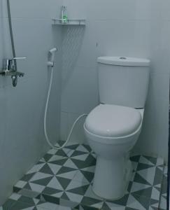 a white toilet in a bathroom with a shower at Quanza Hotel in Banda Aceh
