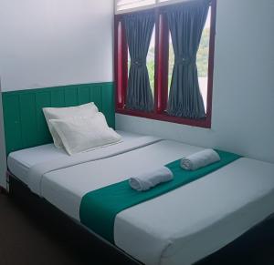 two beds in a room with two towels on them at Quanza Hotel in Banda Aceh