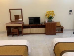 a room with two beds and a tv and a mirror at Đông Thành Hotel in Hòa Ðình