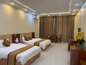 a hotel room with two beds and a table at Đông Thành Hotel in Hòa Ðình