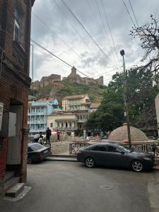 two cars parked on a street in front of a mountain at Sabir's Apartment Old Town in Tbilisi City