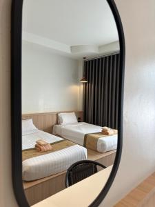 a mirror reflecting two beds in a hotel room at Diamond Park Inn Chiangrai & Resort in Chiang Rai