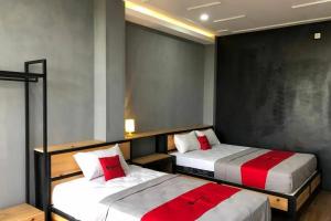 - une chambre avec 2 lits dotés d'oreillers rouges et blancs dans l'établissement RedDoorz near Universitas Muhammadiyah Purwokerto 2, à Kembaran