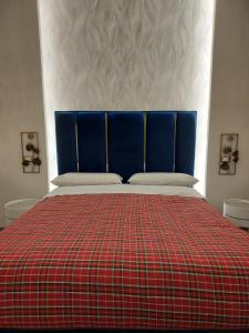 un letto con testiera blu e coperta rossa a scacchi di Suite al Borgo ad Aversa