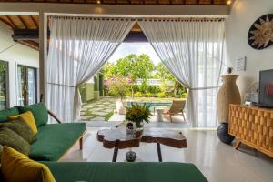 a living room with a green couch and a table at CASTELU 3BR peacefully villa near Mertanadi in Seminyak