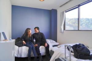 a man and woman sitting on beds in a room at ゲストハウス CYCLE&STAY in Tokushima