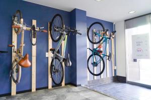 3 vélos suspendus sur un mur dans une pièce dans l'établissement ゲストハウス CYCLE&STAY, à Tokushima