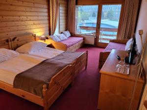 a bedroom with two beds and a couch and a window at La Tour d'Aï in Leysin