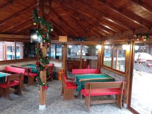 a restaurant with tables and chairs and christmas decorations at Къща за гости "Там край реката " in Slivek