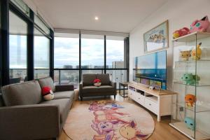 ein Wohnzimmer mit einem Sofa und einem TV in der Unterkunft Pokémon Inspired Apt -Pool-Gym-Sauna-Steam Room in Adelaide