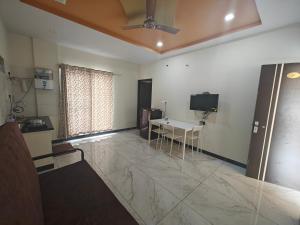 a living room with a table and a television at Comfort Cove Apartments in Mysore