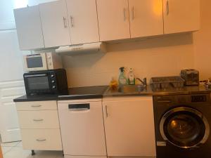 a kitchen with a microwave and a sink and a washing machine at La Maison des roses in Nanterre