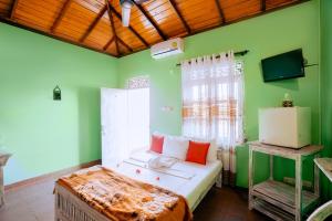 1 dormitorio con paredes verdes y 1 cama con almohadas rojas en Frangipani motel, en Galle