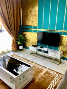 uma sala de estar com uma televisão de ecrã plano e uma mesa em AAIRA Troika Residence,Kota Bharu em Kota Bharu