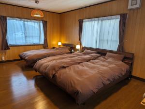 2 letti in una camera da letto con due finestre di 龍のお宿 