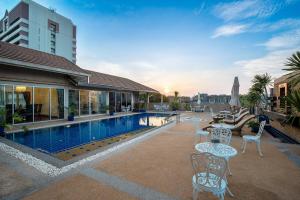una piscina con mesas y sillas junto a un edificio en Capitel Rama 4, en Bangkok