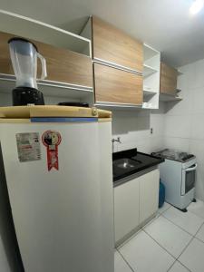 La cuisine est équipée d'un réfrigérateur blanc et d'un évier. dans l'établissement Temporada CG - Apartamento no Alto Branco, à Campina Grande