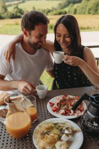 a man and a woman sitting at a table with food at Apartmány HRÁDEČEK in Mladé Buky