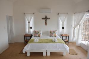 1 dormitorio con 1 cama y 1 cruz en la pared en Alte Kalkoefen Lodge en Simplon