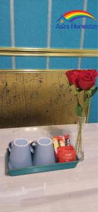 哥打巴魯的住宿－AAIRA Troika Residence,Kota Bharu，盘子上放两个杯子,花瓶上放玫瑰