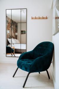 Adriana Zaton في Zaton: كرسي مخملي أخضر في غرفة مع مرآة
